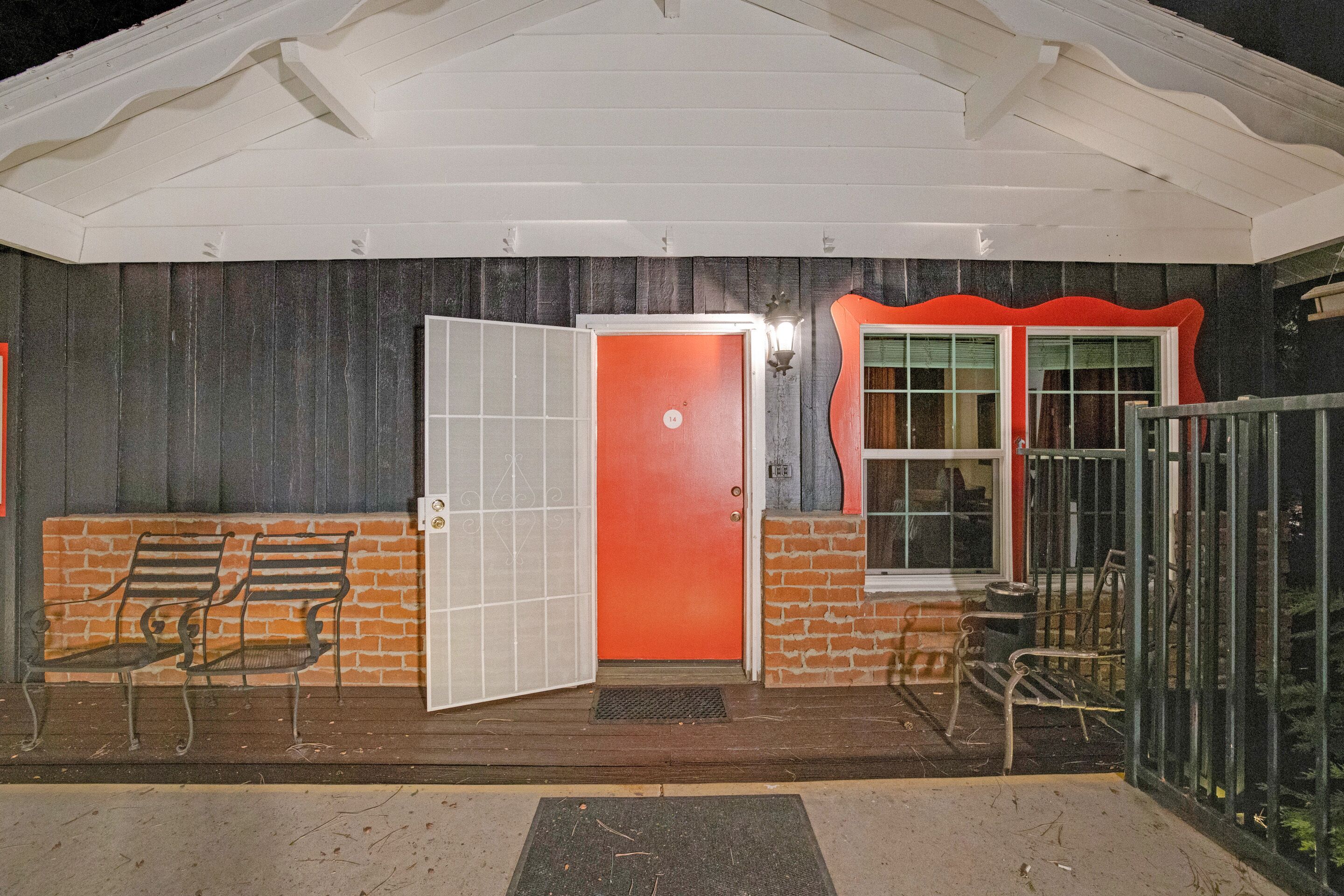 A building with a red door, a white porch, and a brick wall.