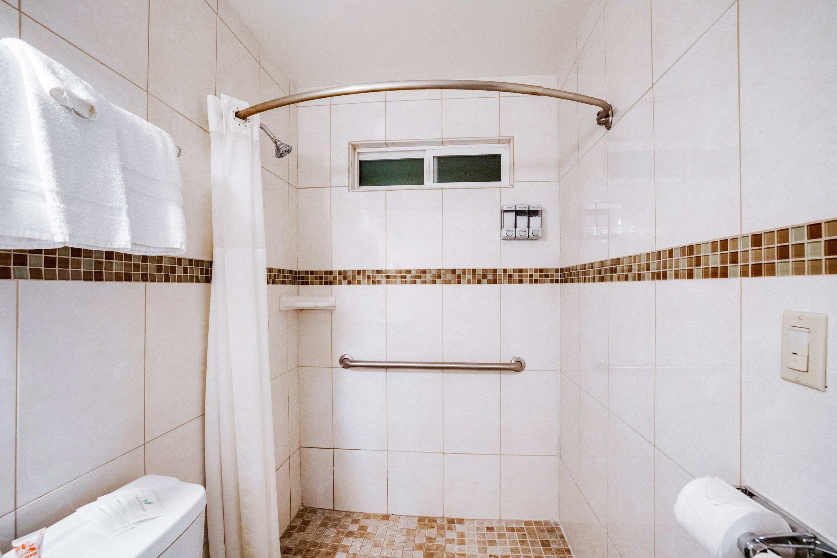 Un baño con ducha, inodoro y un perchero para toallas.