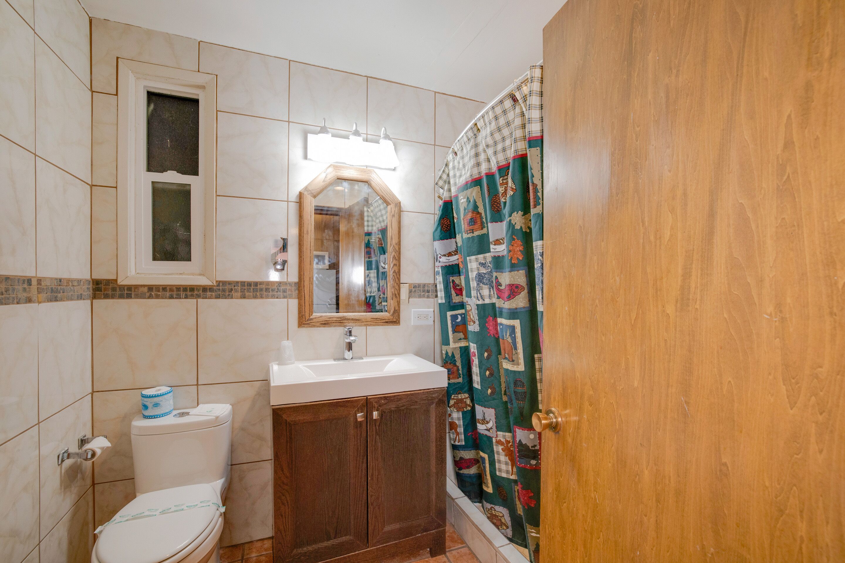 A bathroom with a toilet, sink, mirror, and shower curtain.