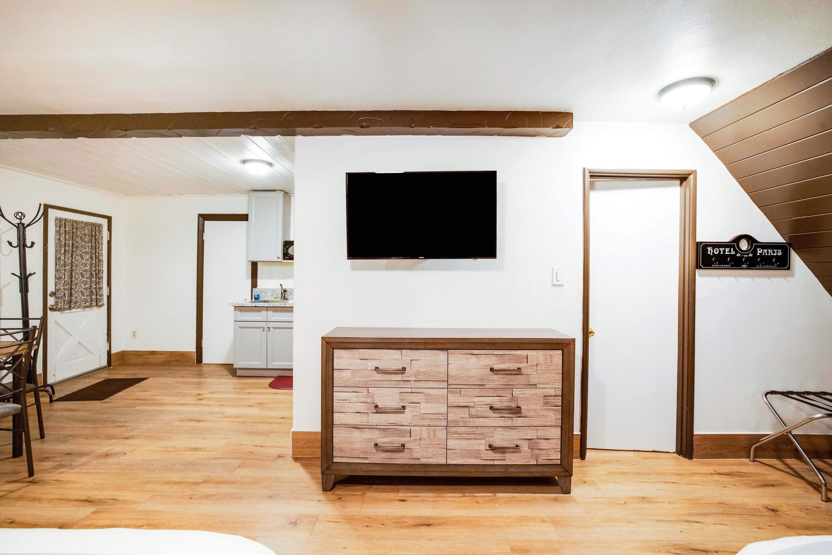 Habitación de hotel con un aparador de madera, un televisor de pantalla plana montado en la pared y un cartel con el nombre del hotel.