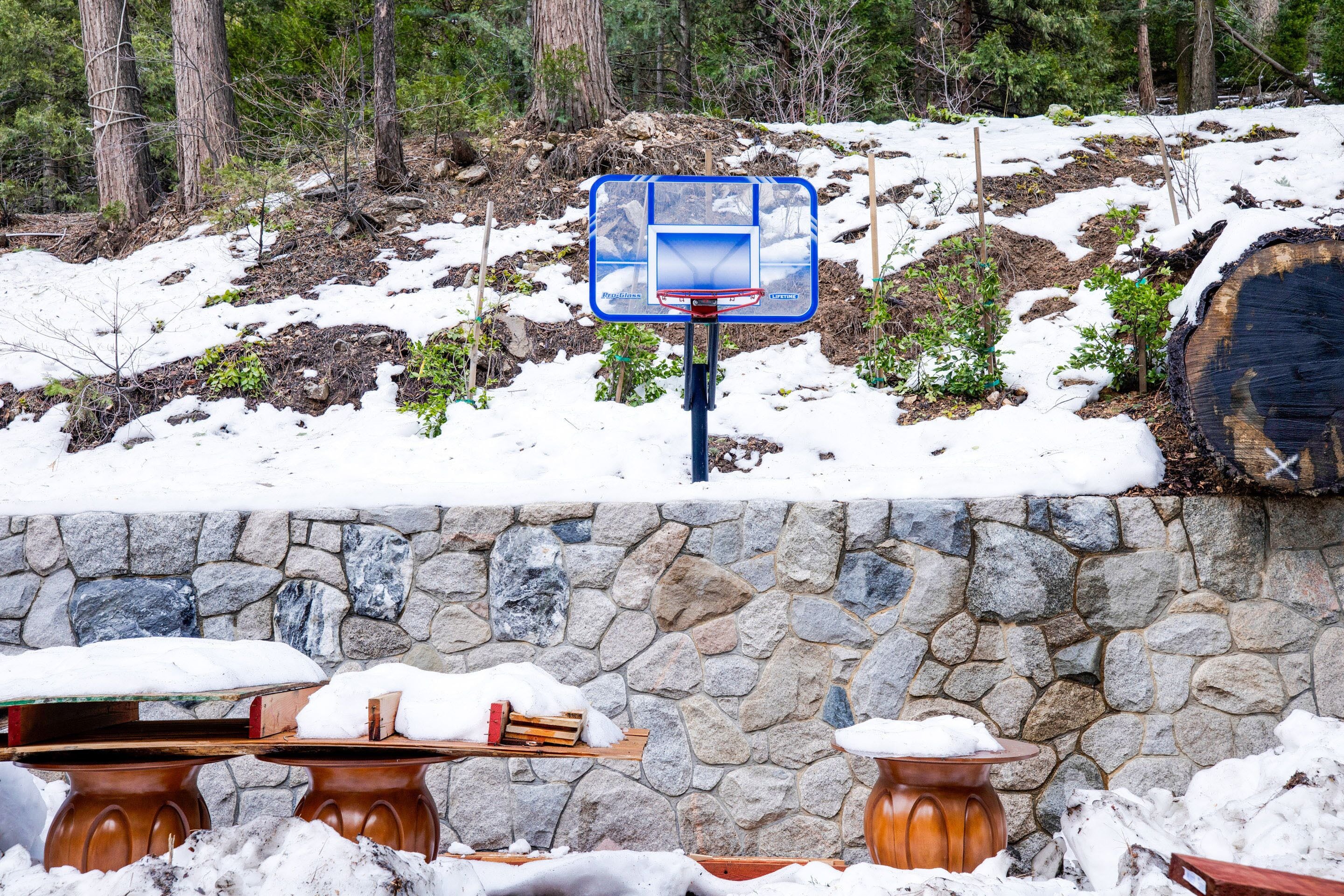 A snow-covered outdoor area with a stone wall and wooden tables.