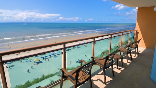 A balcony with a view of a beach and pool area.