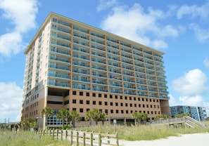 A multi-story hotel with balconies, a beach view, and a wooden walkway leading to the entrance. - Bahama Sands Luxury Condominiums (North Myrtle Beach)