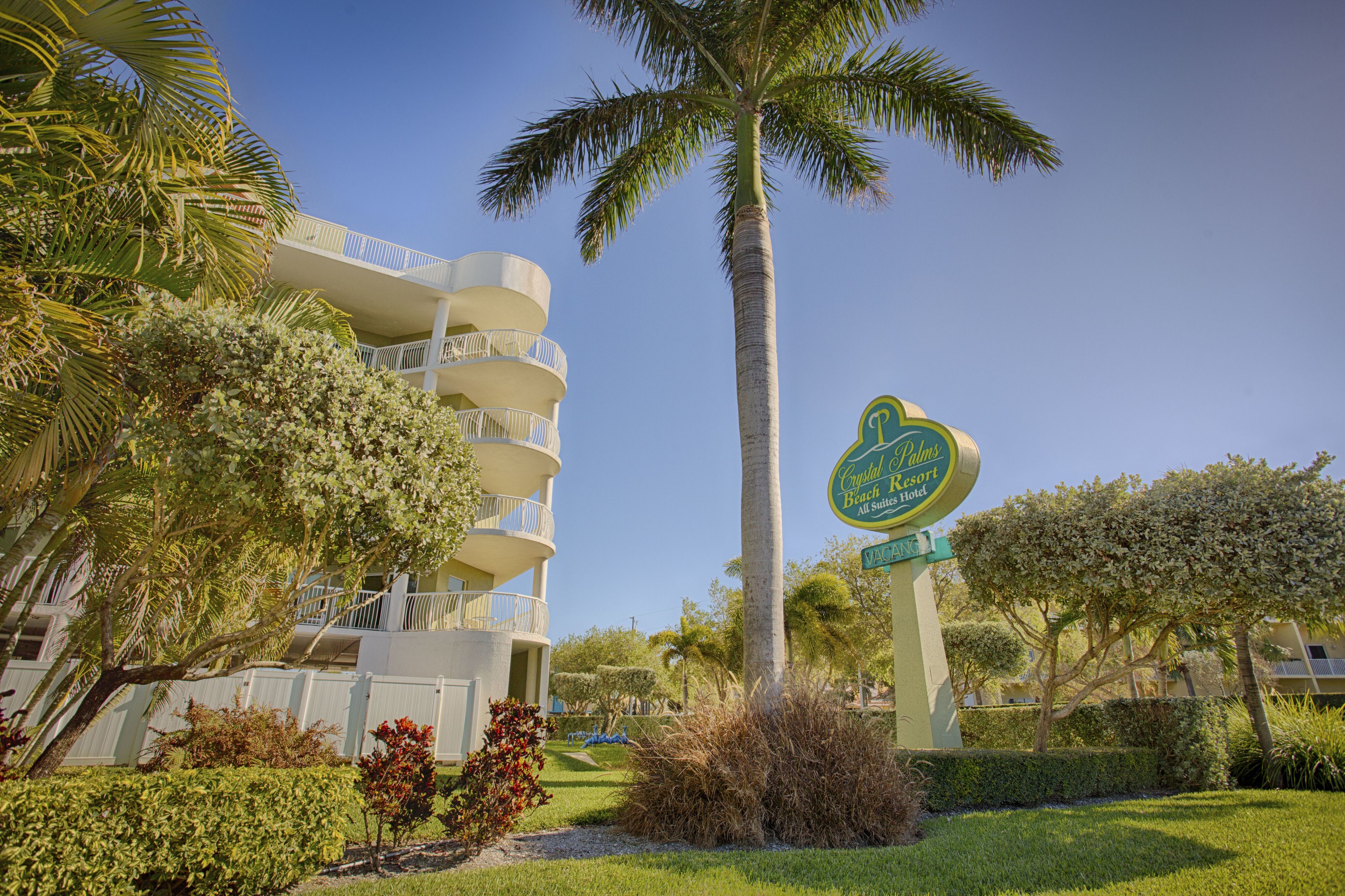 A multi-story hotel with a palm tree and well-maintained landscaping.