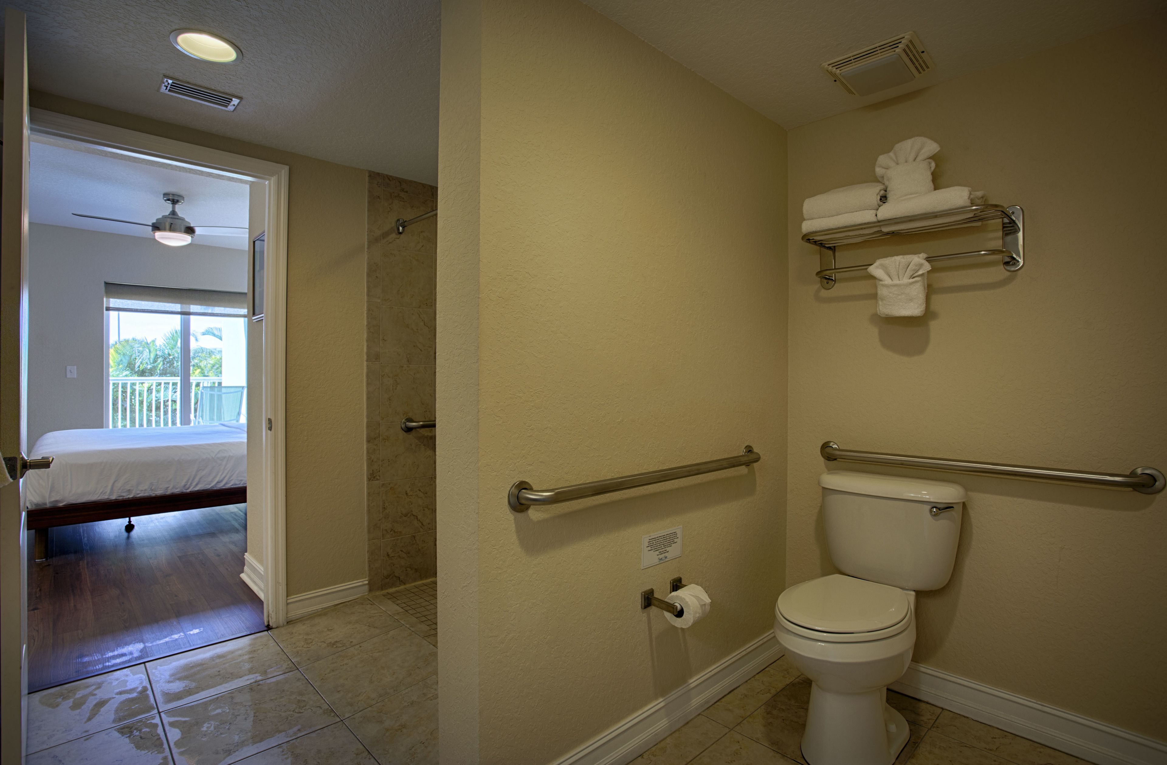 Une salle de bain équipée de toilettes, de barres d’appui et d’un porte-serviettes.