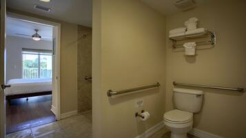 A bathroom with a toilet, handrails, and a towel rack.