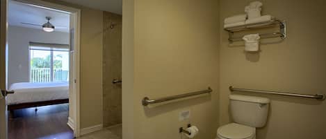 A bathroom with a toilet, handrails, and a towel rack.