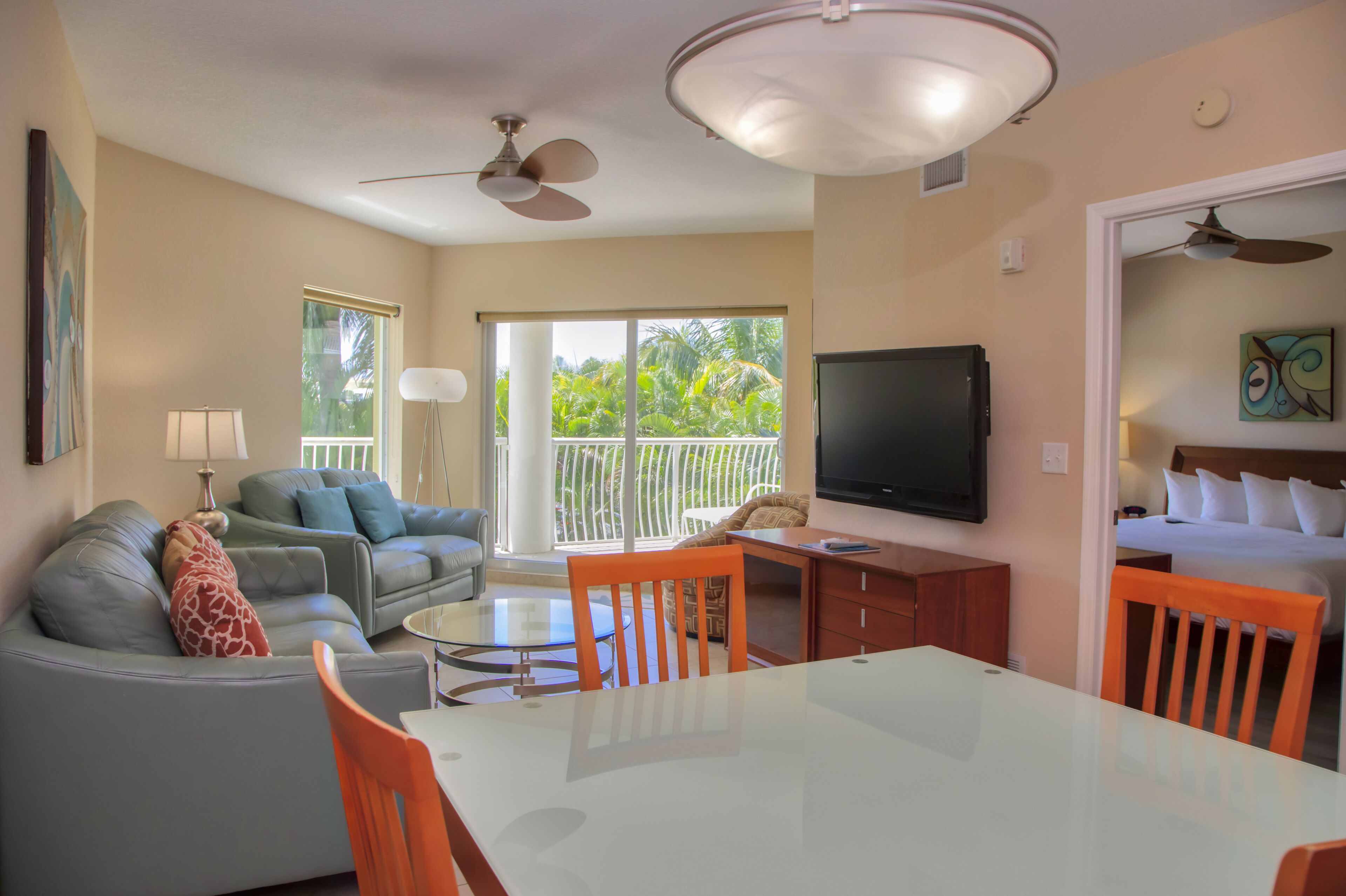 A living room with a sofa, coffee table, TV, and dining area with chairs and a table.