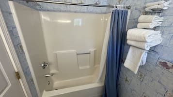 Een badkamer met een badkuip, een douchegordijn en een handdoekrek met handdoeken.