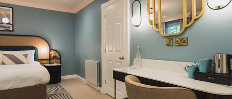 A bedroom with a bed, a desk, a chair, a radiator, a door, and a mirror.