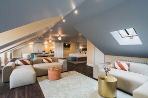 A modern living room with a loft bedroom, a skylight, and a cozy seating area. - Grange Hotel (Grange-over-Sands)