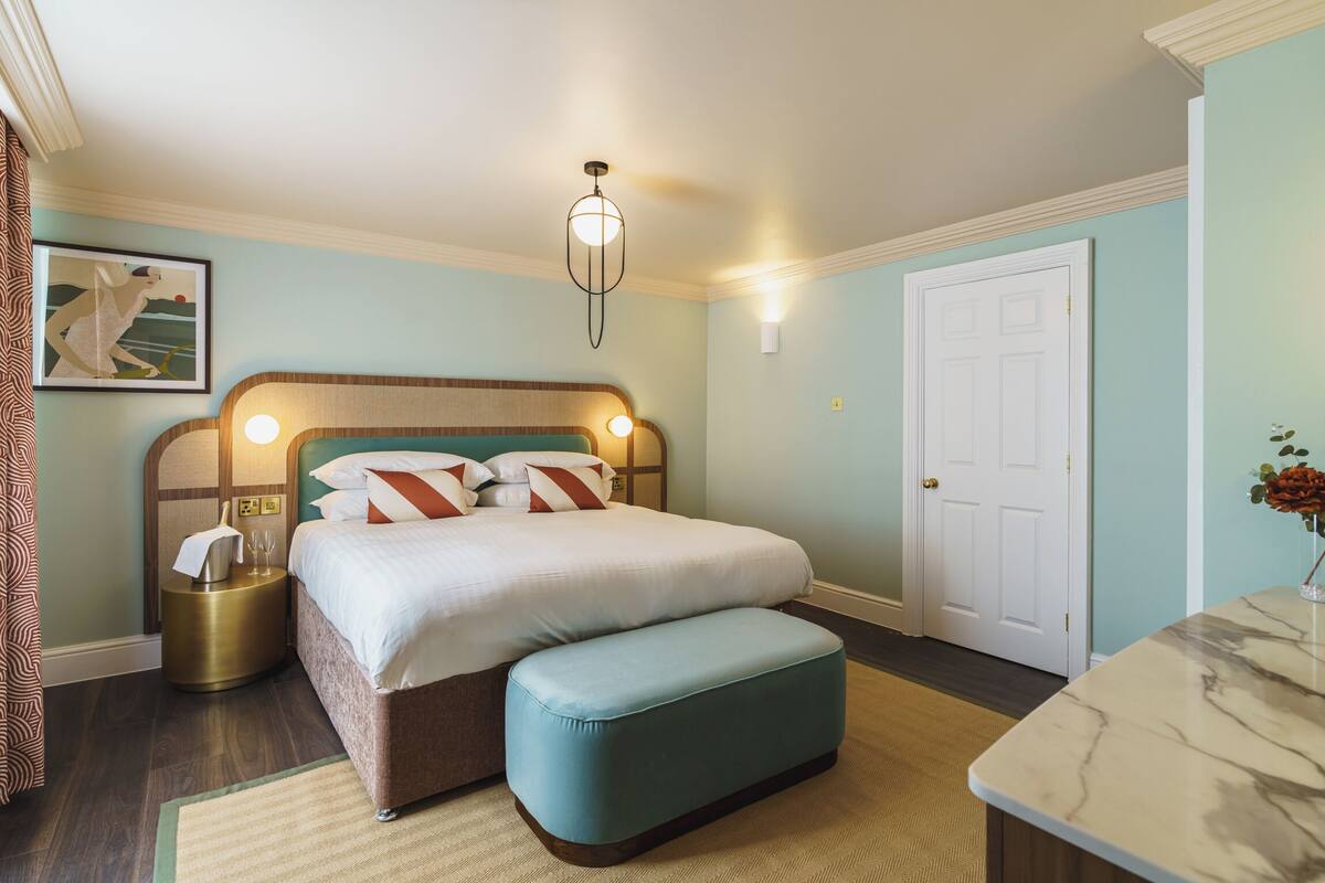 Um quarto com cama, mesa de cabeceira e criado-mudo.