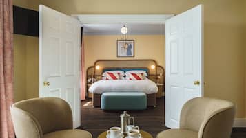 Habitación de hotel con cama, dos sillones, una mesita de café y un cuadro en la pared.