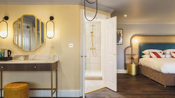 A hotel room with a bathroom, a vanity with a mirror, a bed, and a nightstand with a vase.