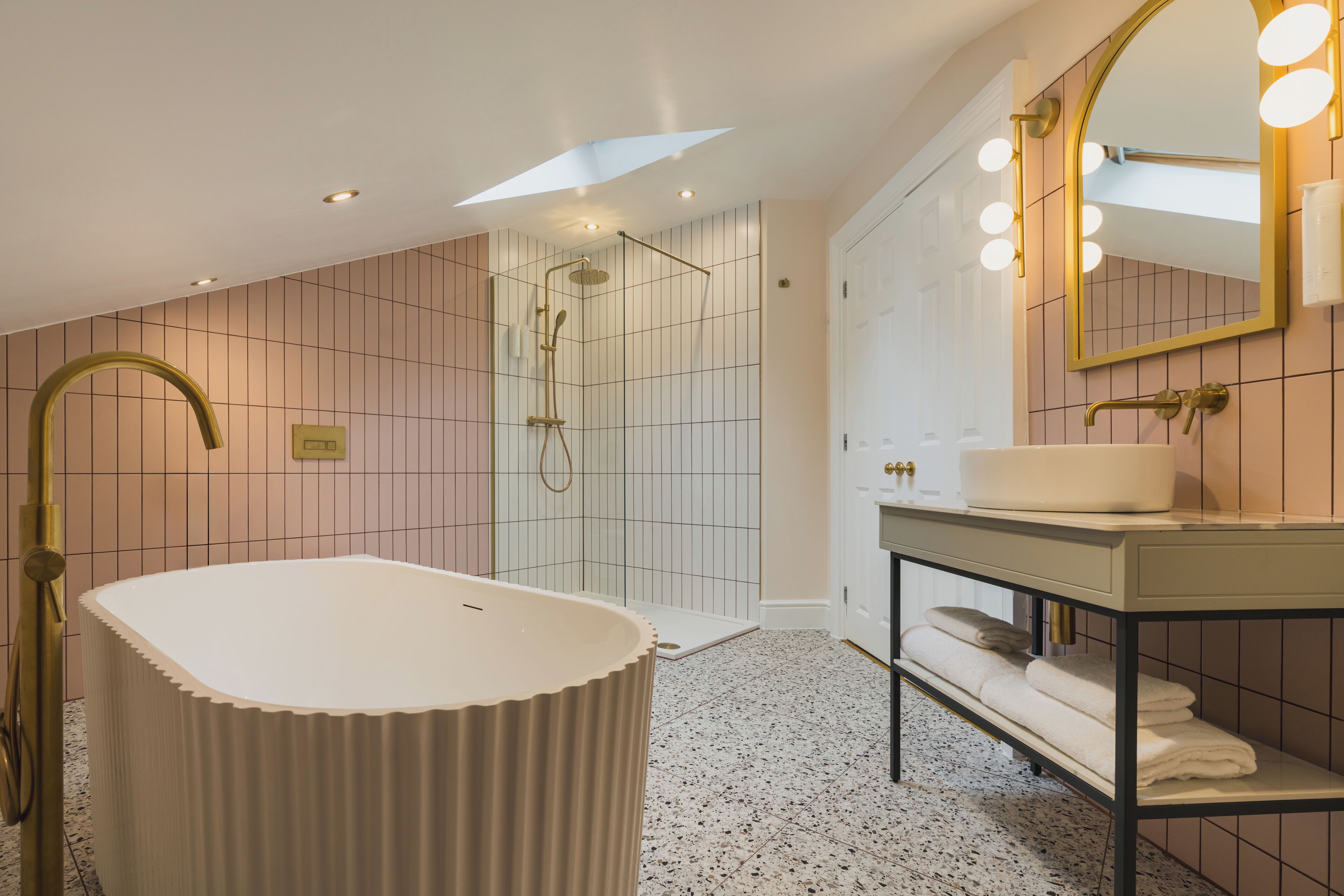 A modern bathroom with a freestanding bathtub, a walk-in shower, and a vanity with a mirror.