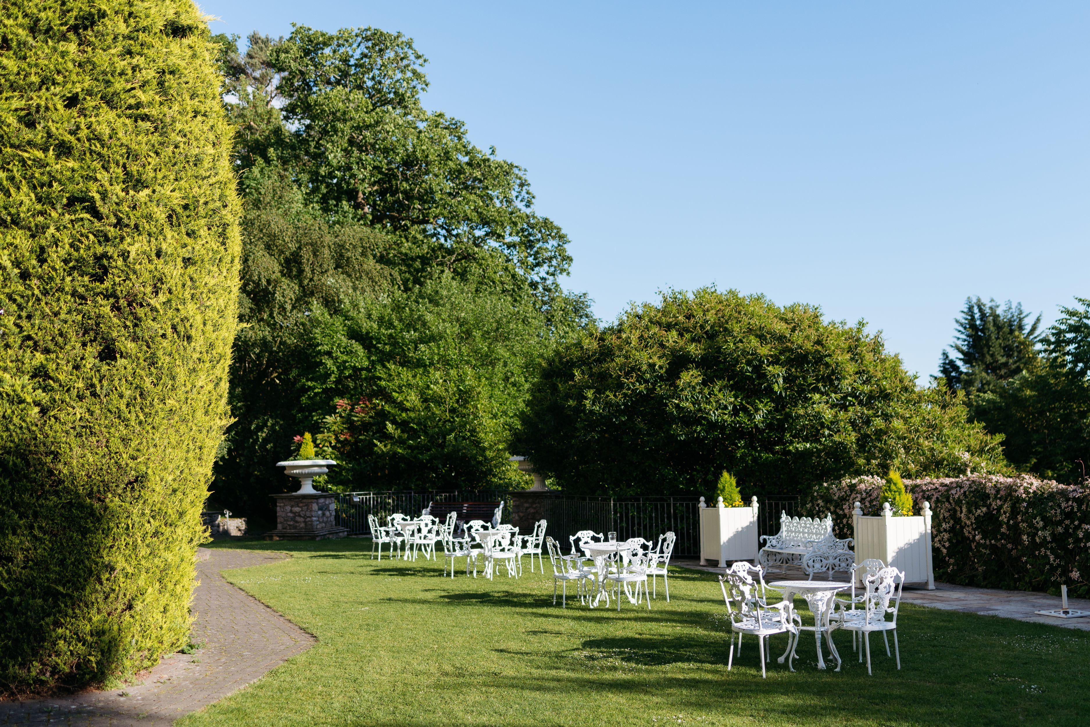 A garden with white outdoor seating and a fountain.