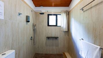 Un área de ducha con ventana, un perchero y un cabezal de ducha.