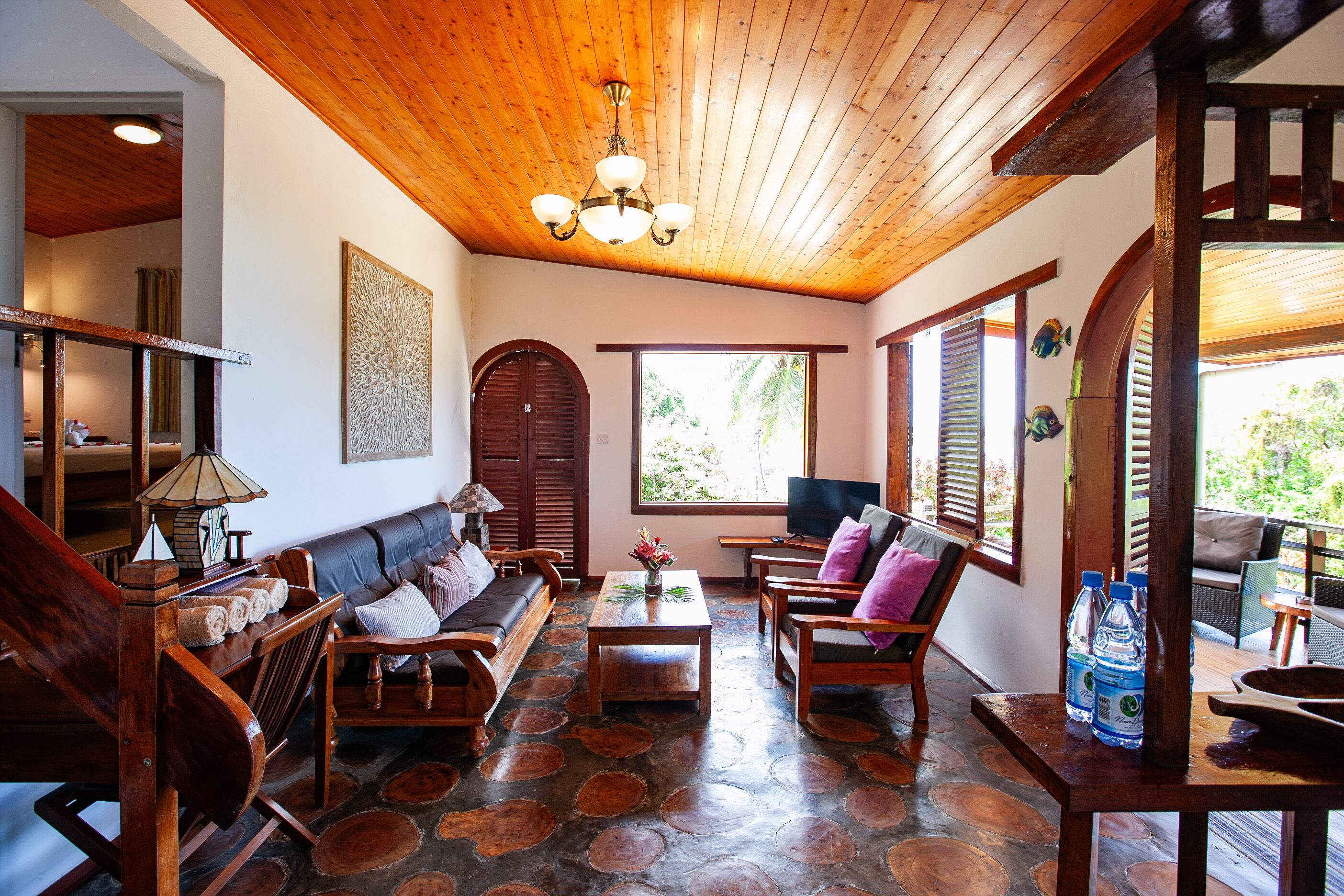 A wooden ceiling, a sofa, a table, and a TV in a room with a view.