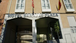 Hotel Barajas Plaza met een gevel van baksteen, grote ramen en twee vlaggen.