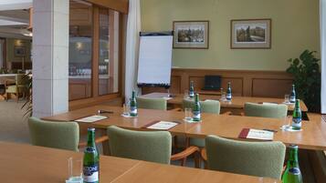 Ein Konferenzraum mit Tischen, Stühlen, einem Projektor und einer Whiteboard-Tafel.