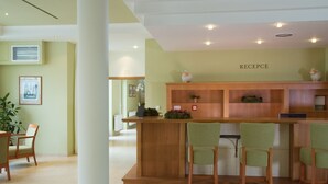 A reception area with a wooden counter, green upholstered chairs, and a 'RECEPTION' sign on the wall. - Dolce Villa Hotel (Prague)