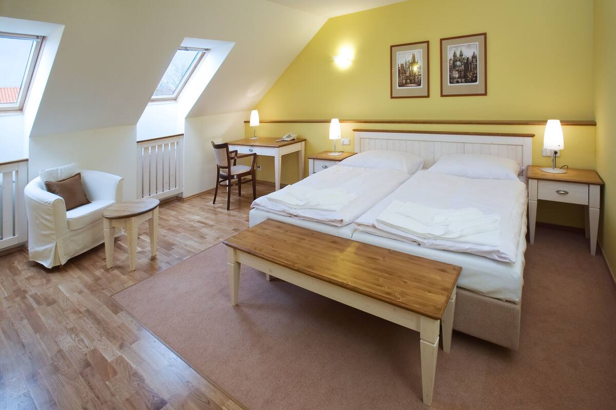 A bedroom with a bed, bedside tables, a desk, a chair, and a bench.