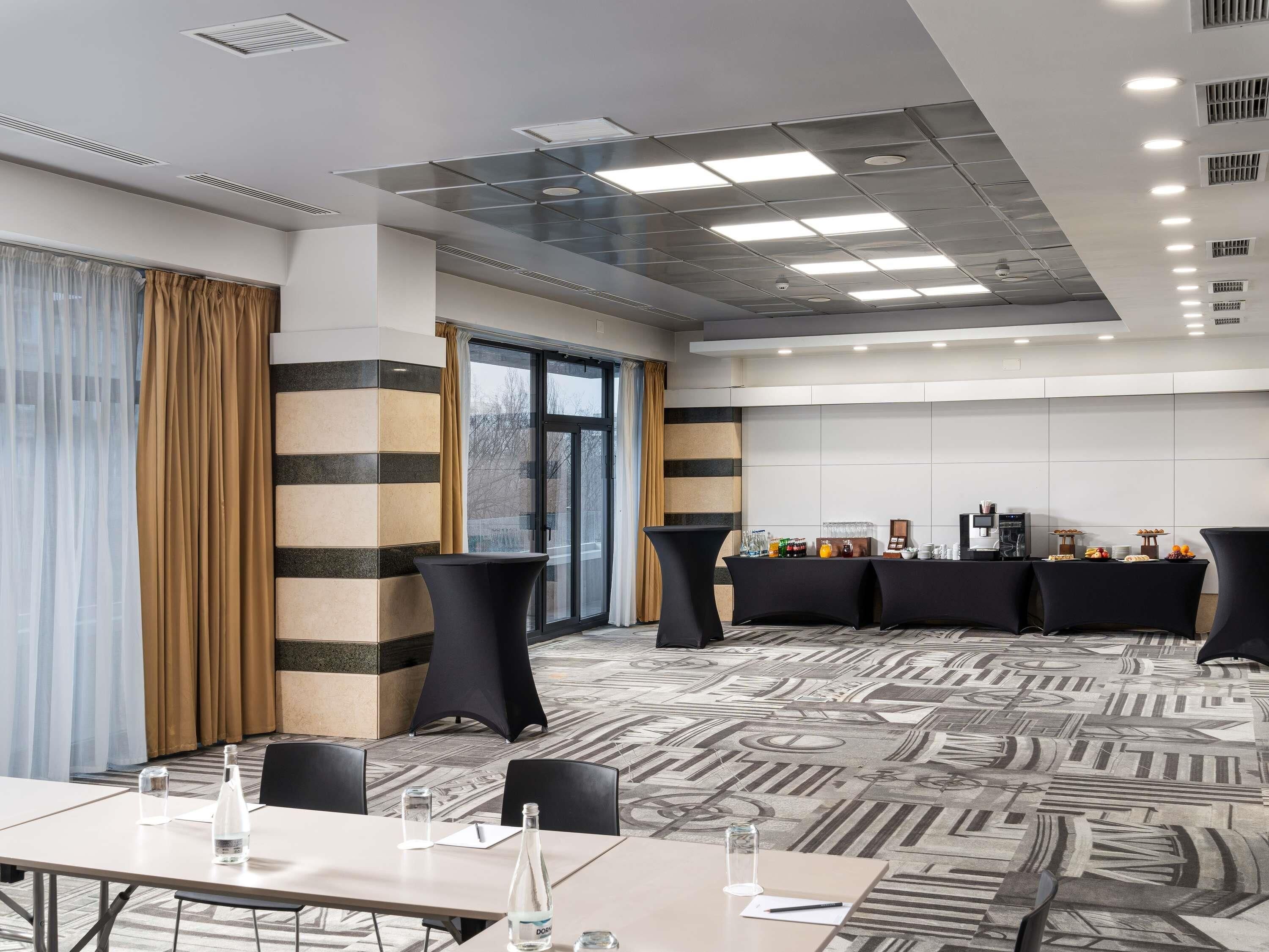 A conference room with a long table, black chairs, a buffet area with food and drinks, and a patterned carpet.