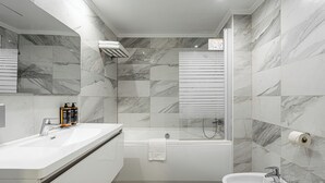 Un baño moderno con un lavamanos blanco, un bidé y una bañera.