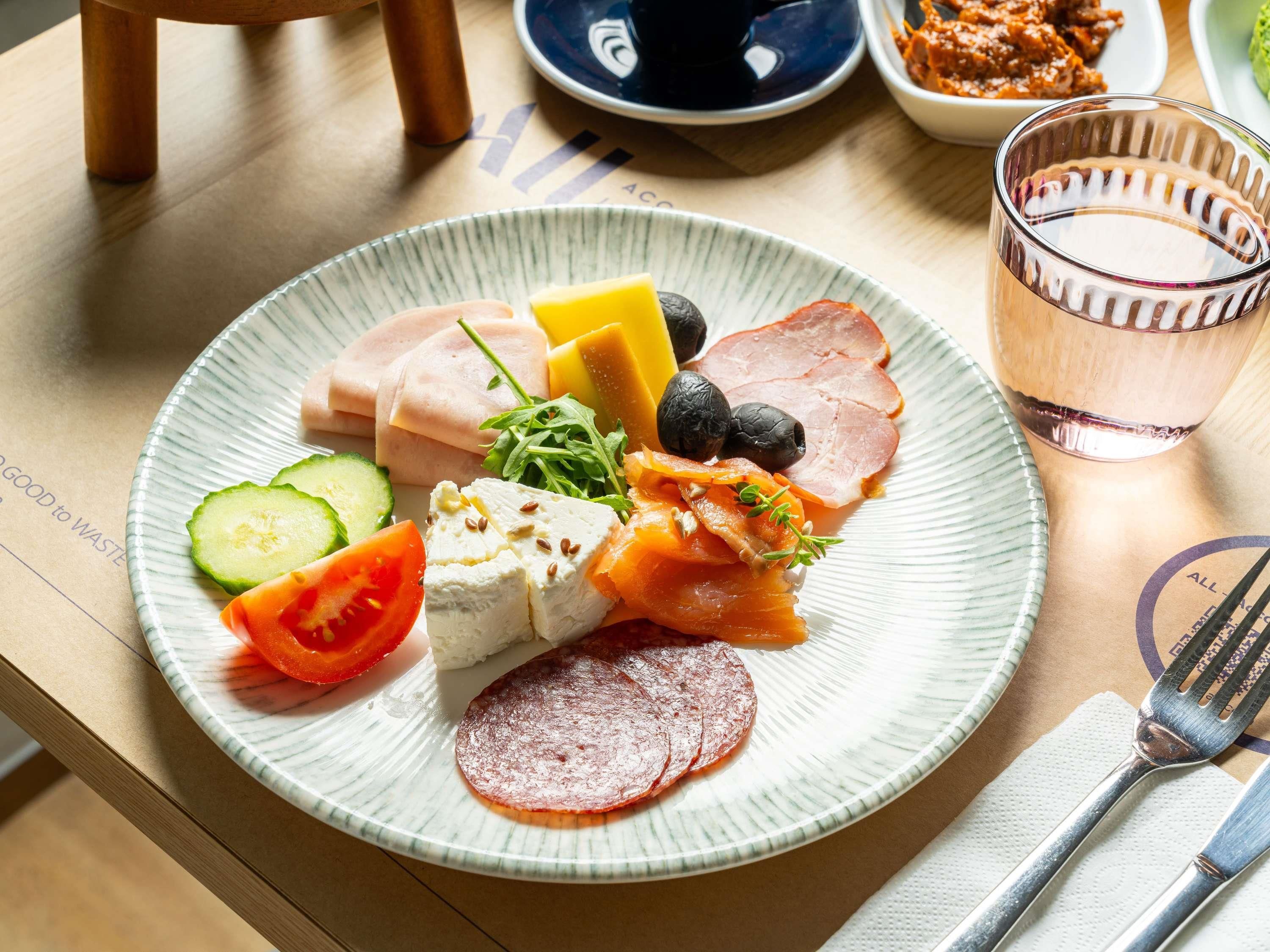 A plate with various cheeses, cured meats, and vegetables.