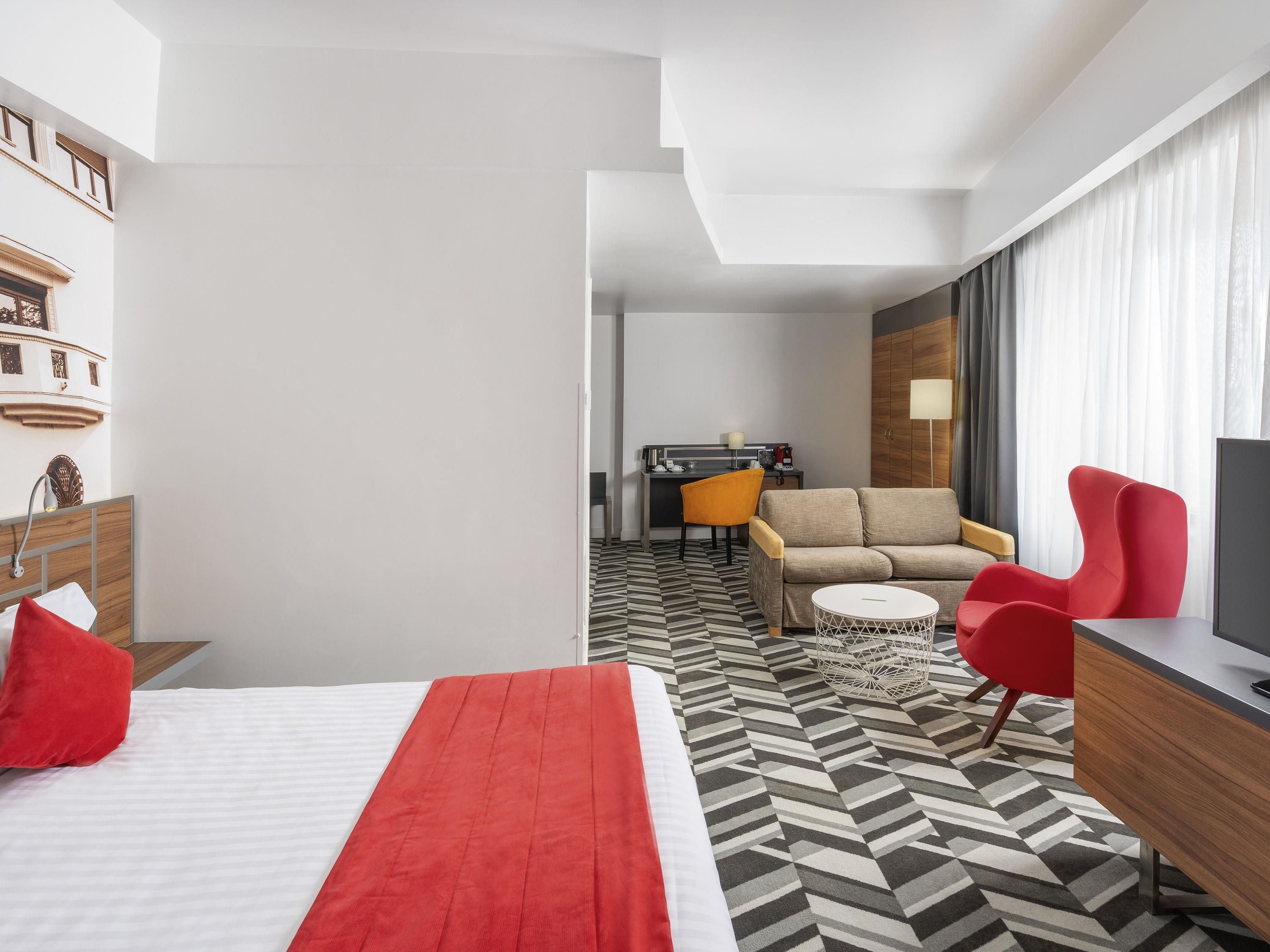 Una habitación de hotel con cama, sofá, escritorio y televisor.