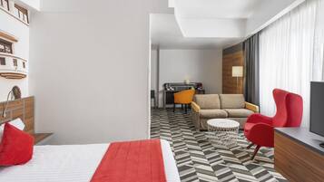 Una habitación de hotel con cama, sofá, escritorio y televisor.