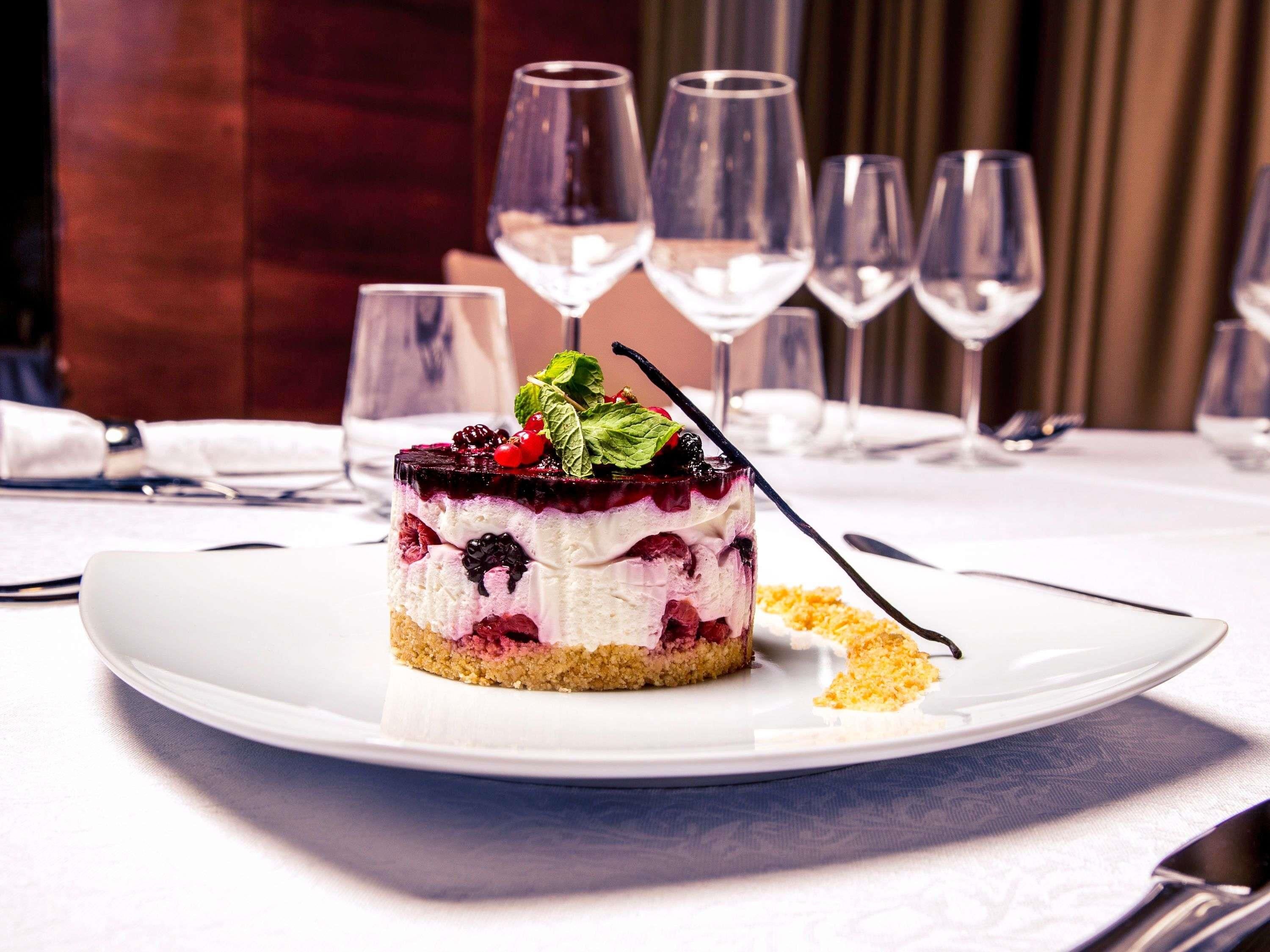 Un postre sobre un plato blanco, con un tenedor y una cuchara a un lado, colocado sobre una mesa con mantel blanco.