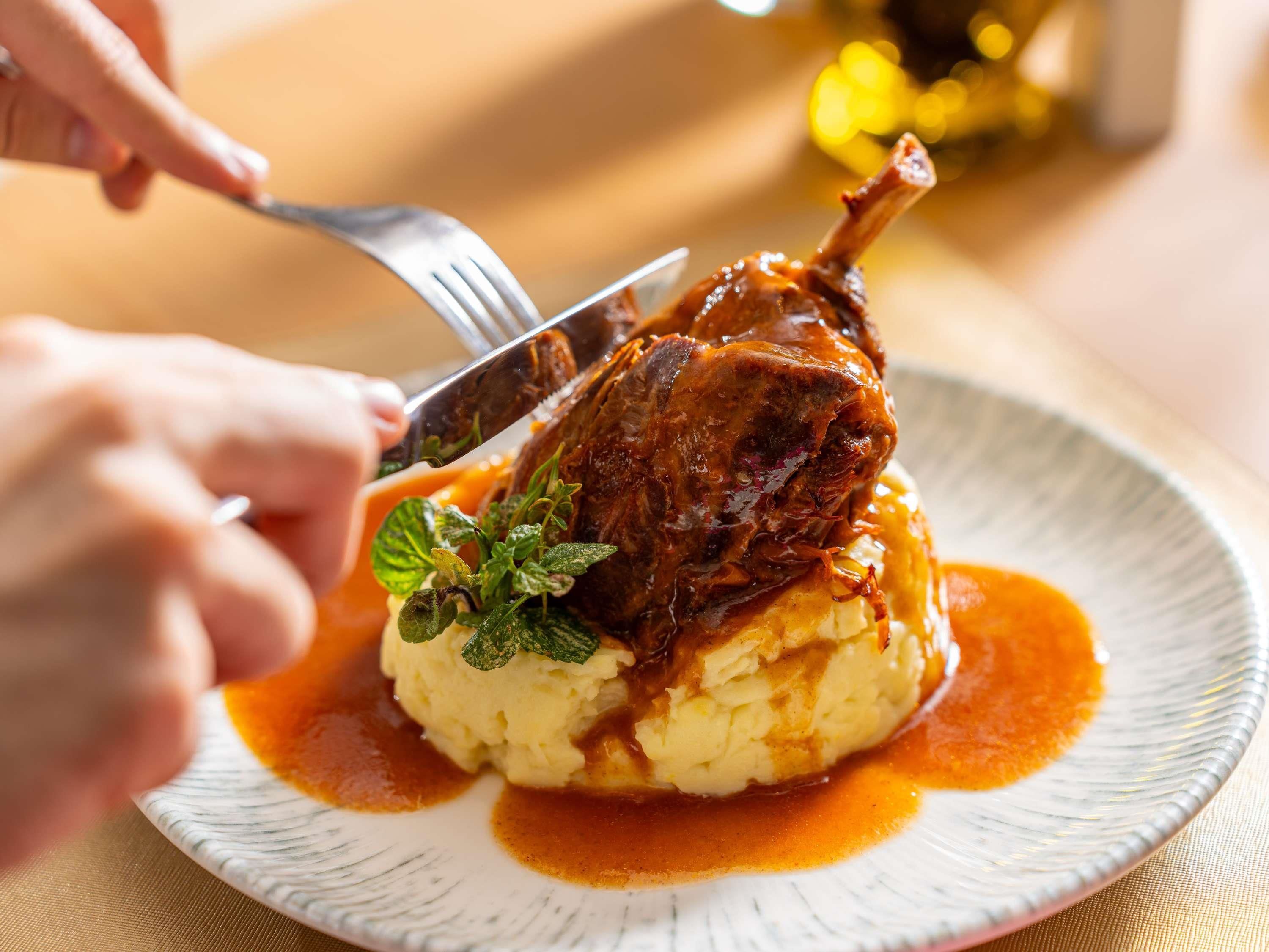 A plate with mashed potatoes, a roasted meat, and a garnish.
