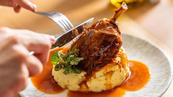 A plate with mashed potatoes, a roasted meat, and a garnish.