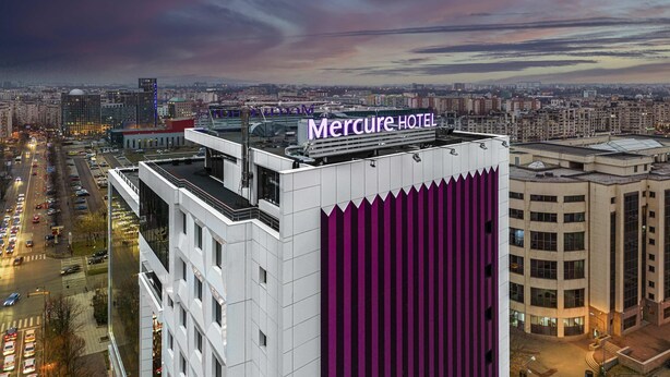 Un edificio alto con un cartel llamativo que dice "Mercure Hotel".