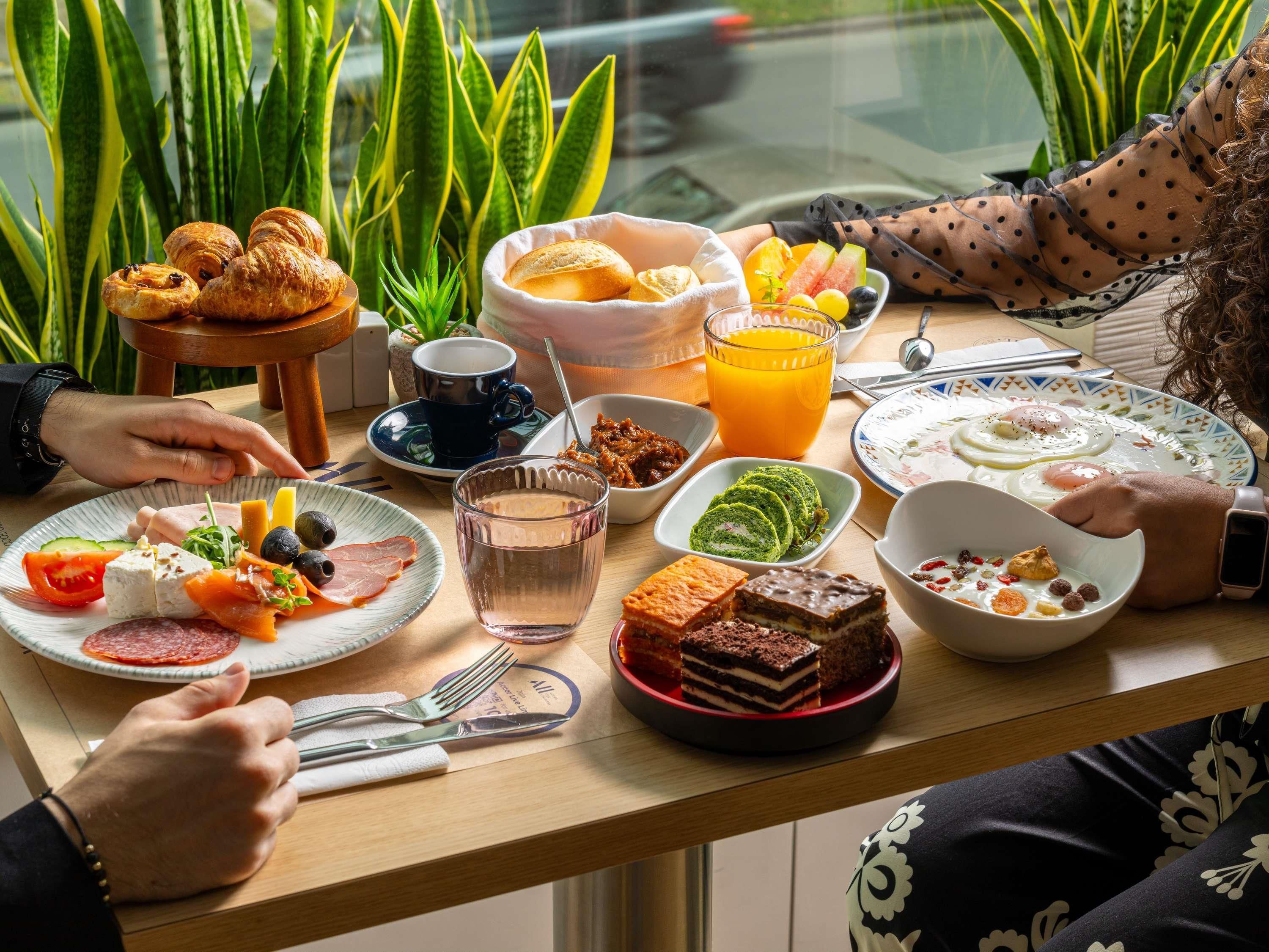 A breakfast table with croissants, fruit, eggs, and various spreads.