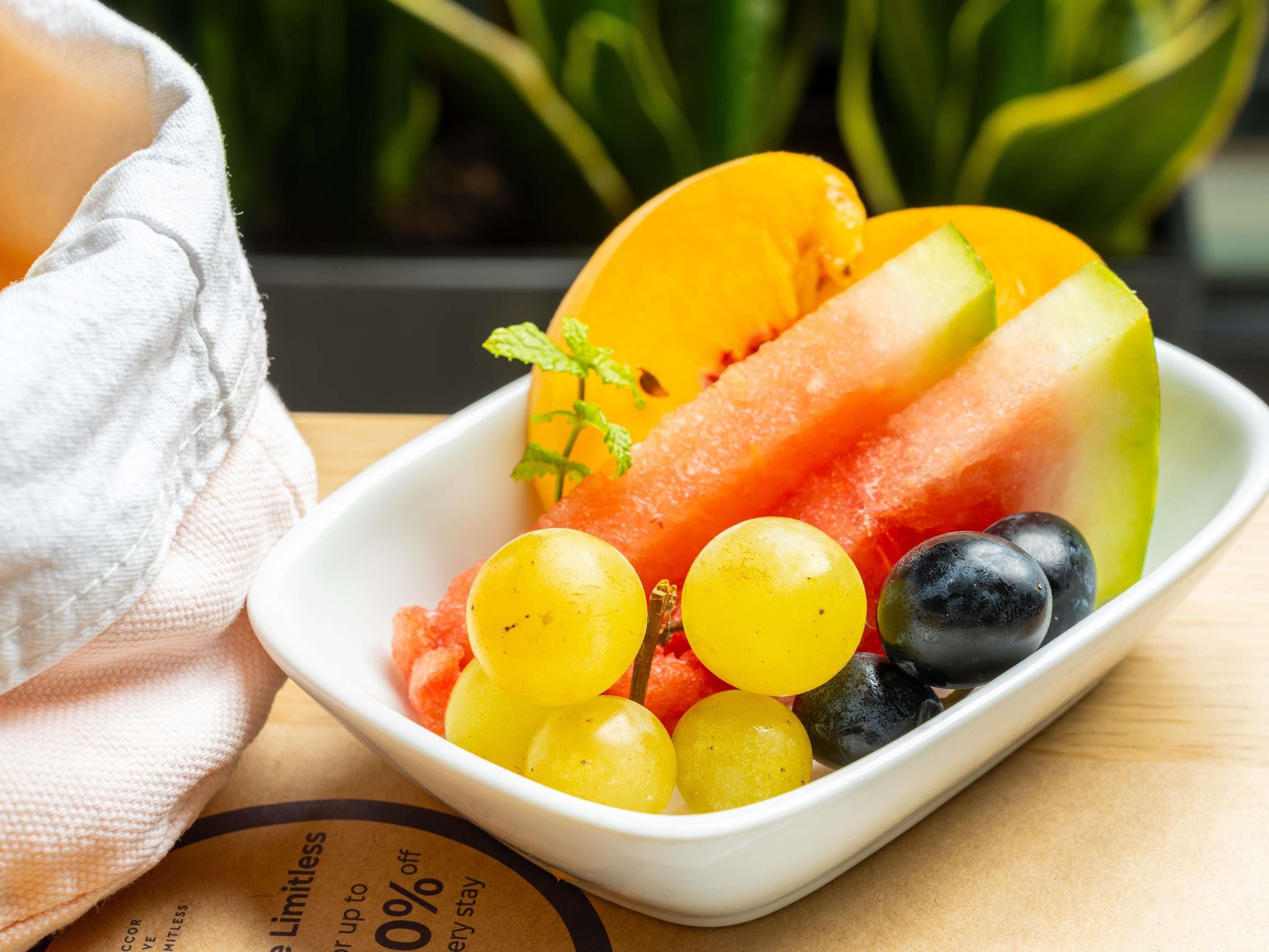 A white rectangular dish containing sliced cantaloupe, grapes, and watermelon.