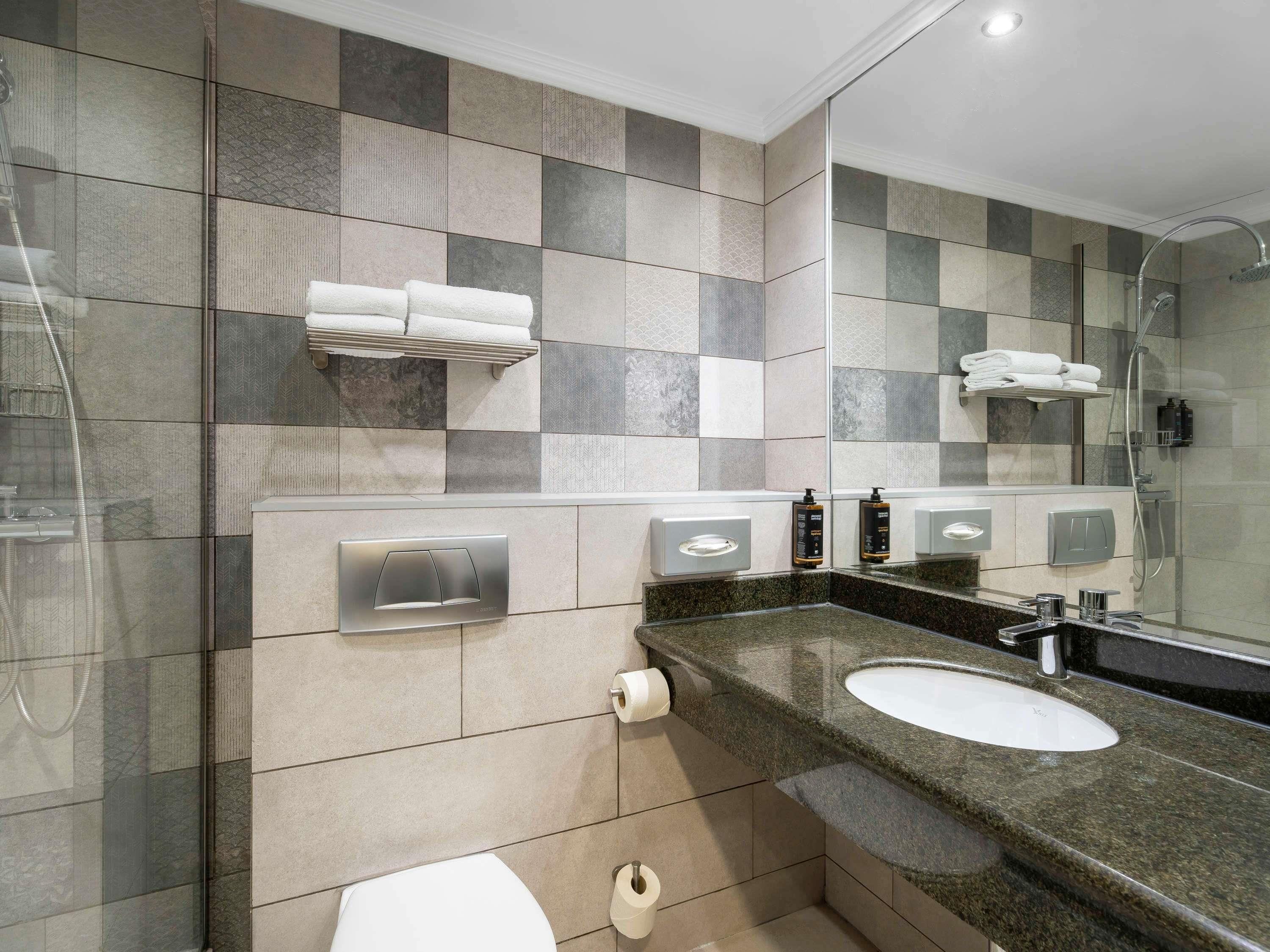 A modern bathroom with two sinks, a toilet, a shower, and a mirror.