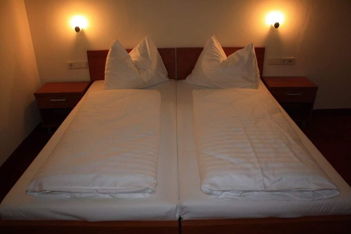 Una cama doble con dos mesitas de noche, cada una con una lámpara de pared.