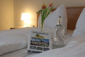 A neatly made bed with a brochure titled "Information" and a bottle of water on it. - Hotel-Restaurant Marienhof (Sankt Andrae-Woerdern)