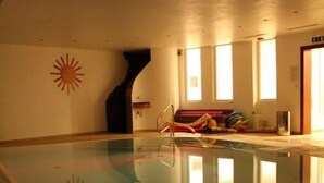 Una piscina con un diseño de sol en la pared, un vestuario con perchero y una puerta que da a otra habitación.