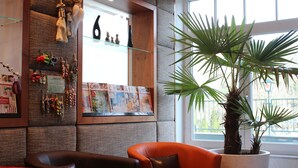Un área de recepción con zona de estar, exhibición de artesanías locales y una planta grande en maceta junto a la ventana.