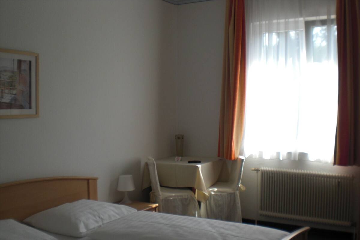 Una habitación de hotel con dos camas, un escritorio, una silla, una lámpara y un radiador.