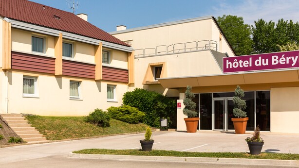 Un hotel con techo rojo, paredes color beige y un letrero que dice 