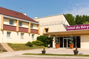 Un hotel con techo rojo, paredes color beige y un letrero que dice 