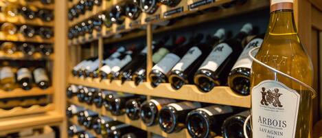 A wine rack filled with various bottles, prominently featuring a bottle labeled "Arbois Savignin 2014".