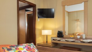 Una habitación de hotel con una cama, un escritorio con lámpara, una televisión y un espejo.