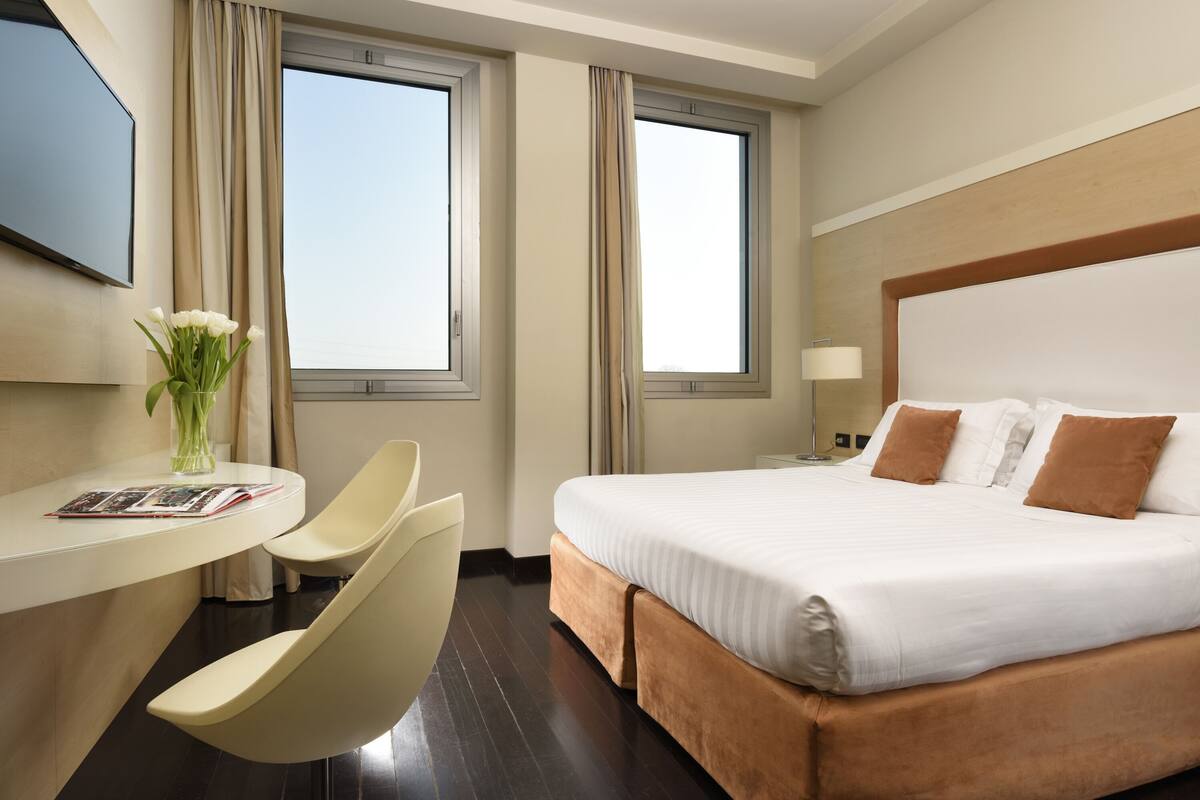 Una habitación de hotel con cama, escritorio, silla y televisor.