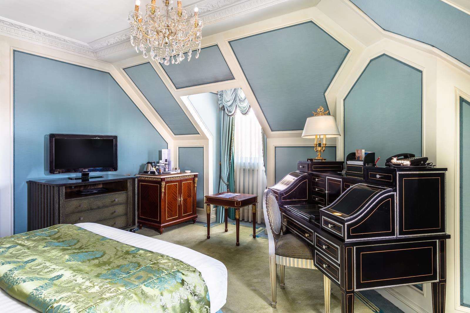 Un dormitorio con una cama grande, un escritorio con lámpara, un televisor y un aparador.