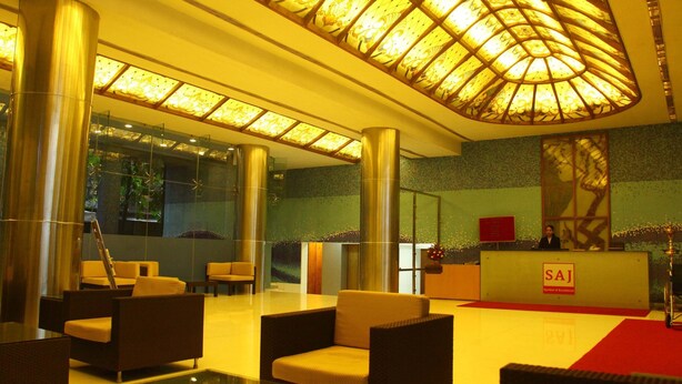 A lobby with a reception desk, seating area, and a large glass wall. - Saj Luciya (Thiruvananthapuram)